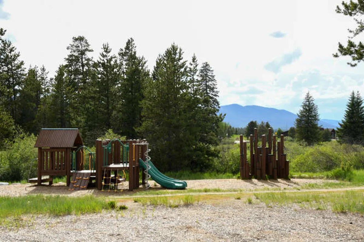 A vibrant outdoor playground featuring slides and other play equipment, surrounded by natural scenery and open spaces ideal for family gatherings and children's play.